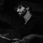 Black and white shot of Producer's Toolbox composer, Jarrod Pedone, playing drums.