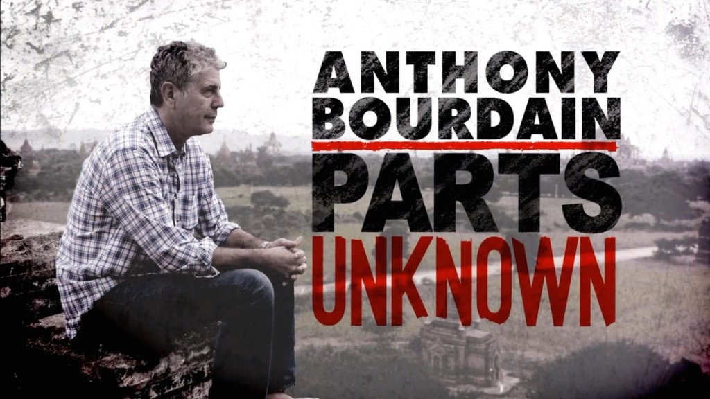 Still of profile of Anthony Bourdain in a flannel shirt sitting on a rock wall by the road and staring off into the distance with the words "Anthony Bourdain: Parts Unknown" overlaid to his right. Flavorlab Score and Producer's Toolbox provided original music and music licensing for the series.