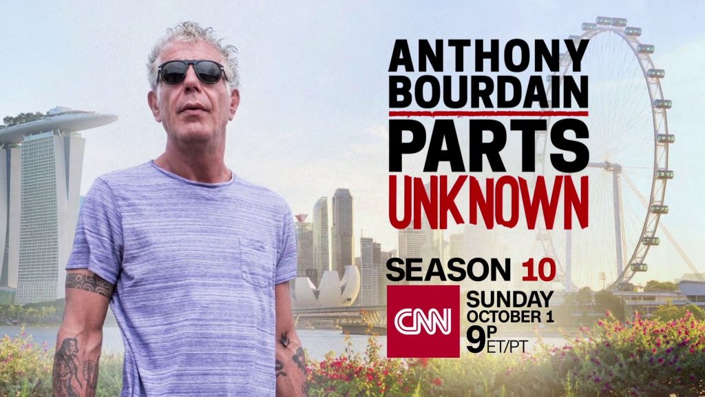 Still of Anthony Bourdain staring above the camera wearing sunglasses in front of a city skyline and ferris wheel. Flavorlab Score provided original music for the series.